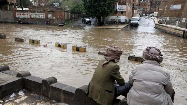 epa11553383 People sit near a flooded street following heavy rains in Sana'a, Yemen, 17 August 2024. Heavy rains and flash floods have hit large parts of Yemen over the past two weeks, leaving about 98 people killed and over 600 others injured, according to a statement by the United Nations. EPA/YAHYA ARHAB