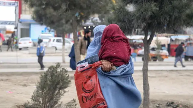 epa11324546 A burqa clad Afghan woman carries a child on a road in Kabul Afghanistan, 07 May 2024. Australia announced on 03 May it had committed to offering aid of AUD 492 million (USD 323 million) to reduce poverty in countries of the Indo-Pacific region through a fund from the Asian Development Bank. Australia has defended placing emphasis on mitigating the effects of the climate crisis and on the inclusion of new mechanisms to ensure the arrival of aid to people in Afghanistan, Myanmar and the Rohingya ethnic minority displaced in Bangladesh, with special emphasis on women and girls. EPA/SAMIULLAH POPAL