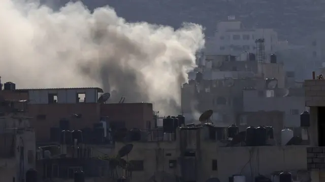 epa11580235 Smokes rises over Jenin refugee camp during the sixth day of an Israeli military operation in the West Bank city of Jenin, 02 September 2024. According to the Palestinian Health Ministry, at least 27 Palestinians have been killed since Israeli military operations started on 28 August 2024 in the West Bank cities of Tulkarem, Jenin, and Tubas. The Israeli army said that it's conducting a large-scale 'counterterrorism operation' in several areas. EPA/ALAA BADARNEH