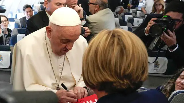 epa11580735 Pope Francis (L front) signs autographs on a cloth for a journalist, aboard the flight bound for Jakarta, the first stop of his Apostolic Journey to Southeast Asia, 02 September 2024. Pope Francis is set to begin his 12-day visit to four countries in Asia and Oceania. During his 45th Apostolic Journey, the Pontiff will visit Indonesia, Papua New Guinea, East Timor and Singapore until 13 September 2024. The Pope will clock 32,814 kilometers (20,390 miles) by air during his 02-13 September visit to Indonesia, Papua New Guinea, East Timor and Singapore, far surpassing any of his previous 44 foreign trips and notching one of the longest papal trips ever, both in terms of days on the road and distances traveled. EPA/GREGORIO BORGIA / POOL