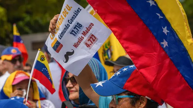 epa11569292 Protesters hold signs and flags during a demonstration organized by Venezuelan opposition leader Maria Corina Machado in front of the Basilica of Our Lady of Chiquinquira in Maracaibo, Venezuela, 28 August 2024. EPA/HENRY CHIRINOS