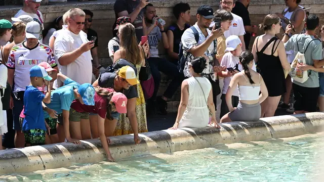 Turisti nella morsa del caldo a Fontana di Trevi. Roma, 13 agosto 2024. ANSA/CLAUDIO PERI