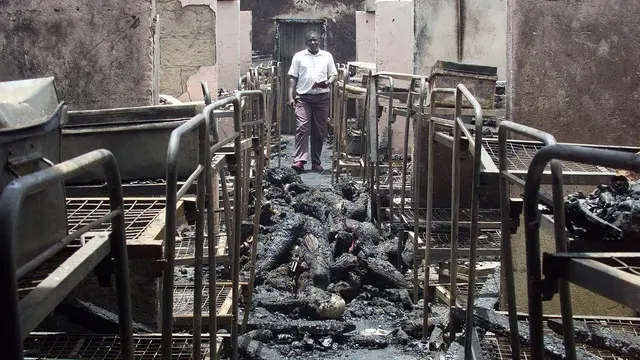 A man walks through the dormitory of Kyanguli Secondary School containing the burned corpses of dozens of students in Machakos east of Nairobi March 26, 2001. A Kenyan police officer said he suspected arson caused a fire that killed 58 teenaged boys. REUTERS/Antony Njuguna