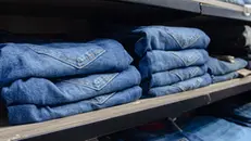 Jeans di varie taglie impilati su uno scaffale - Foto unsplash.com