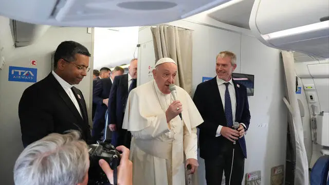 Pope Francis, center, flanked by his spokeperson Maeo Bruni, right, talks to journalists, Monday, Sept. 2, 2024, aboard the flight bound to Jakarta, Indonesia, where Francis will start his 12-day pastoral visit to Asia. Francis will clock 32,814 kilometers (20,390 miles) by air during his Sept. 2-13 visit to Indonesia, Papua New Guinea, East Timor and Singapore, far surpassing any of his previous 44 foreign trips and notching one of the longest papal trips ever, both in terms of days on the road and distances traveled. (AP Photo/Gregorio Borgia, pool)