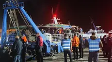 Un peschereccio con a bordo 400 migranti circa attracca al molo commerciale di Lampedusa dopo che nel pomeriggio è avvenuto un naufragio con otto dispersi e la morte di una bimba, Lampedusa, Italia, 20 novembre 2023. Ad agganciarlo e scortarlo, garantendo la sicurezza di tutte le persone a bordo, sono state le unità di soccorso della Guardia costiera. In questo momento sta per iniziare lo sbarco di donne, bambini ed uomini che saranno poi trasferiti all'hotspot. Salgono così ad 11, per un totale di oltre 800 persone, gli sbarchi di oggi sulla maggiore delle isole Pelagie. ANSA / ELIO DESIDERIO