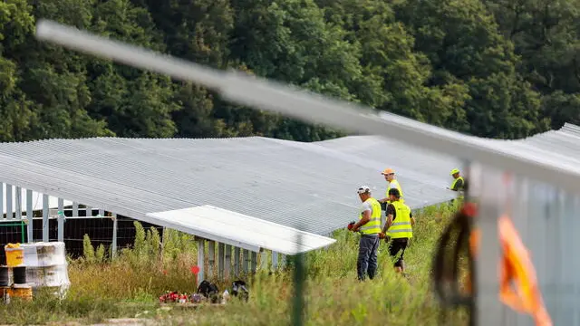 epa11527559 Workers install parts of an open-space photovoltaic system (solar park) at the construction site close to Petershagen in the east of Berlin, Germany, 05 August 2024. According to the German Federal Statistical Office, in April 2023, around 2.7 million PV systems were supplying renewable electricity from rooftops and properties in Germany. By April 2024, approximately 3.4 million photovoltaic systems had been installed, representing an increase of approximately 30 percent compared to the previous year. EPA/HANNIBAL HANSCHKE