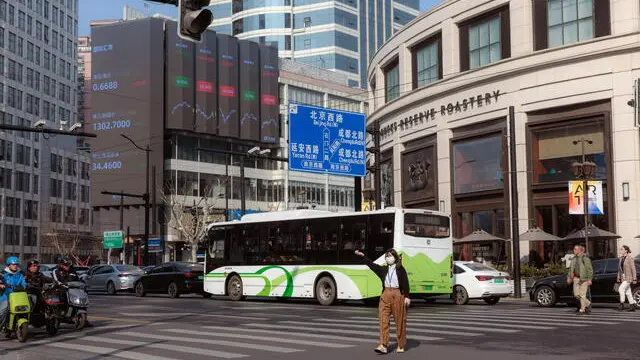 epa10523508 People cross the street near a large screen showing the latest stock exchange data, in Shanghai, China, 15 March 2023. Asia-Pacific markets sank on 14 March after the fallout of failed banks in the US, including Silicon Valley Bank. On 15 March, Asian markets are higher as Chinese, and Hong Kong shares show growth. The Shanghai Composite rose 0.63 percent, together with the Hang Seng by 2.14 percent and the Nikkei 225 by 0.27 percent. EPA/ALEX PLAVEVSKI