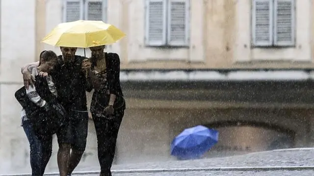 Persone si riparano con l'ombrello durante il violento temporale che ha colpito Roma, 17 giugno 2014. ANSA/ANGELO CARCONI