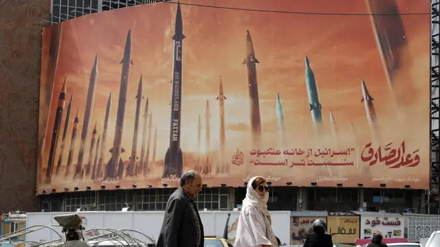 epa11293859 Iranians walk past an anti-Israel billboard carrying pictures of Iranian missiles and a sentence reading in Persian 'Israel is weaker than spider home' in Tehran, Iran, 22 April 2024. Tension between Iran and Israel continue since Iran's Islamic Revolutionary Guards Corps (IRGC) launched drones and missiles towards Israel on 13 April, following an airstrike on the Iranian embassy in Syria which Iran claimed was conducted by Israel. Iranian state media reported that three aerial objects were destroyed by air defense systems over the central city of Isfahan early morning on 19 April. EPA/ABEDIN TAHERKENAREH
