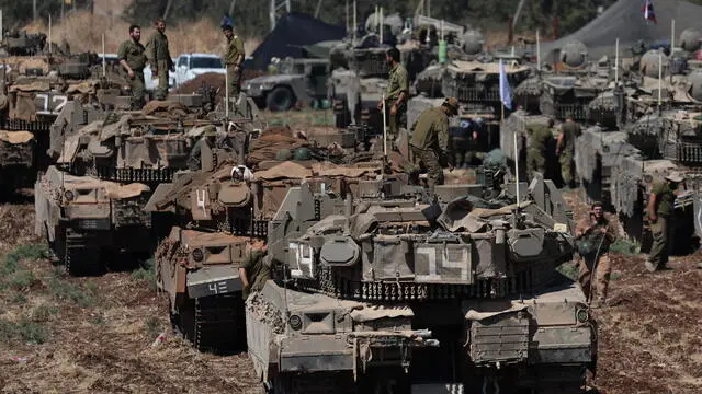 epa11627927 Israeli soldiers with their tanks gather at an undisclosed location in northern Israel, 27 September 2024. Israel's military stated on 27 September, that the Israel Air Force (IAF) launched dozens of strikes targeting Hezbollah cells and infrastructure in several areas in southern Lebanon. EPA/ATEF SAFADI