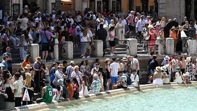 Turisti nella morsa del caldo a Fontana di Trevi. Roma, 13 agosto 2024. ANSA/CLAUDIO PERI