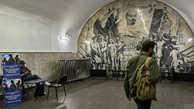 epa11639594 A commuter (R) walks past a volunteer sitting next to an advertising banner reading â€˜Information point - Military service under contract in Moscowâ€™ in an underground passage in Moscow, Russia, 03 October 2024. About 190,000 people signed contracts with the Defense Ministry in 2024, 23,000 of which in Moscow alone, according to Deputy Chairman of the Security Council Dmitry Medvedev and Moscow Mayor Sergei Sobyanin. EPA/SERGEI ILNITSKY