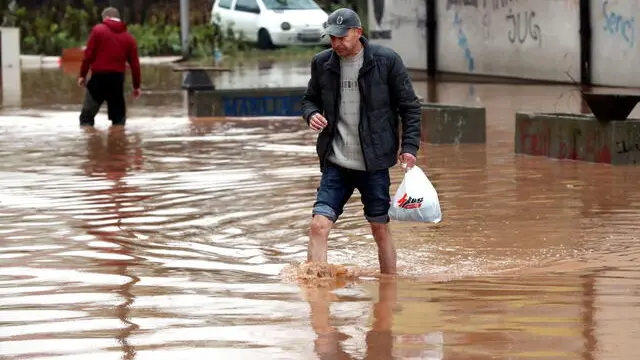 epa09566180 A man crosses a street in the flooded area of Ilidza, Sarajevo, Bosnia and Herzegovina, 05 November 2021. The region has been hit by heavy rains that have caused floods in several areas. EPA/FEHIM DEMIR