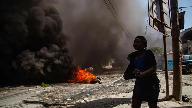 epa11555711 A woman moves past a fire barricade during a protest against gang violence in the Solino neighborhood of Port-au-Prince, Haiti, 19 August 2024. EPA/MENTOR DAVID LORENS