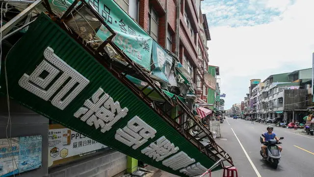 epa11641124 A motorist drives past a broken store sign caused by Typhoon Krathon in Kaohsiung City, Taiwan, 04 October 2024. Typhoon Krathon was downgraded to a tropical storm due to weakening. The Central Emergency Operation Center reported two deaths, 219 injuries, and one missing due to the storm across Taiwan. EPA/RITCHIE B. TONGO