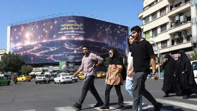 epa11639522 Iranians walk near an anti-Israeli billboard depicting recent Iran's missile attack on Israel and a sentence reading in Persian 'If you want war, we are the master of war', at the Enghelab square in Tehran, Iran, 03 October 2024. Iran fired missiles directed at Israel on the evening of 01 October, state media reported quoting the Islamic Revolutionary Guard Corps (IRGC). The attack was a 'retaliation for different assassinations' carried out by Israel and 'the crimes in Palestine and Lebanon', the IRGC said. According to the Israeli army, more than 180 ballistic missiles were fired against Israel from Iran. EPA/ABEDIN TAHERKENAREH