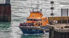 epa10196795 The RNLI (Royal National Lifeboat Institution), British Border Force and military personnel escort migrants ashore at Dover Docks after they crossed the English Channel, in Dover, Britain, 21 September 2022. According to figures released by the UK Ministry of Defence, as of 20 September 2022 the provisional number of arrivals had reached over 29,700, higher than the total of 2021. EPA/STUART BROCK