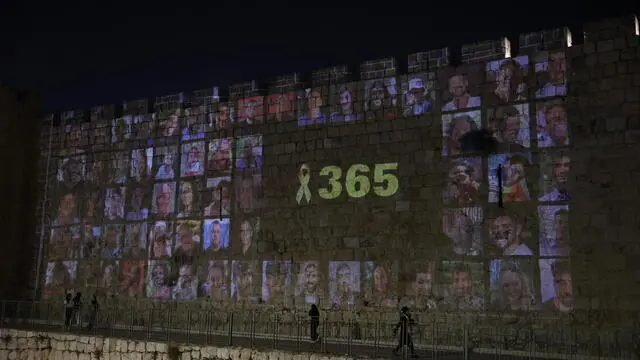 epa11646235 People looks at pictures of 101 Israeli hostages held by Hamas in Gaza projected on the walls of the Old City of Jerusalem, 06 October 2024. Upcoming 07 October 2024 marks one year since the Palestinian militant group Hamas launched a surprise attack on Israel, killing 1,200, and one year since Israel began its war on Gaza, killing more than 41,000 and destroying the Palestinian enclave. EPA/ABIR SULTAN