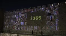 epa11646235 People looks at pictures of 101 Israeli hostages held by Hamas in Gaza projected on the walls of the Old City of Jerusalem, 06 October 2024. Upcoming 07 October 2024 marks one year since the Palestinian militant group Hamas launched a surprise attack on Israel, killing 1,200, and one year since Israel began its war on Gaza, killing more than 41,000 and destroying the Palestinian enclave. EPA/ABIR SULTAN