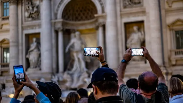 epa11648068 Tourists lean over barriers to photograph the famed Trevi Fountain in Rome, Italy, 07 October 2024. Access to the Trevi Fountain will be limited during the Roman Catholic Jubilee Holy Year of 2025 in a pilot scheme that may lead to the introduction of a fee to see the iconic Roman landmark, Rome Mayor Roberto Gualtieri said on 07 October. The centre-left Democratic Party (PD) official also announced the start of an extraordinary maintenance of the fountain. It will be surrounded by transparent panels but within a month a 'horseshoe' walkway will be installed inside the basin where visitors will be able to walk while enjoying an unprecedented view. EPA/LUCIANO DEL CASTILLO