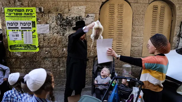 epa11652478 An ultra-Orthodox Jew swings a chicken purchased for the Kapparot ritual in the Mea Shearim neighborhood in Jerusalem, 10 October 2024. Kapparot begins by reciting a prayer and then spinning the bird over their head to release the sins accumulated over the past year, ahead of the high-holiday of Yom Kippur, the Day of Atonement. After the Kapparot ritual is performed the bird is slaughtered and donated to charity. EPA/ABIR SULTAN