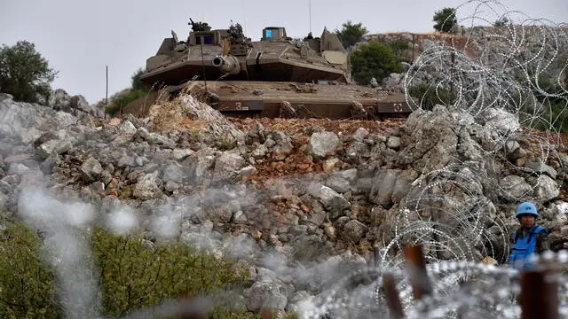 epa10681922 A soldier of the UN peacekeeping mission, United Nations Interim Force In Lebanon (UNIFIL) keeps watches in front of an Israeli Merkava tank during an anti-Israeli demonstration called by Jemaah Islamiyah (Islamic Group) on the border strip with Israel in the Kfar Chouba area, Southern Lebanon, 09 June 2023. Israeli soldiers fired tear gas to disperse the demonstrators who threw stones at the troops on the Lebanese-Israeli border. Tensions at the border began after Israeli caterpillars tried to dig trenches in an area that Lebanon considers to be Lebanese soil. EPA/WAEL HAMZEH