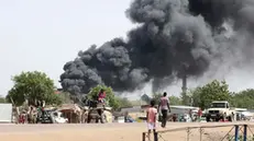 epa10625669 People drive as smoke rises from a fire at a market in the Upper Nile State town of Renk, South Sudan, 13 May 2023. According to UNHCR, at least 40,000 people have arrived into South Sudan since armed clashes between Sudan's military and rival paramilitary groups began in Khartoum and other parts of the country on 15 April 2023. Most of the refugees are part of the some 800,000 South Sudanese who had previously fled the war in South Sudan and who are now returning to a country with tensions still remaining in many areas, and more than two million internally displaced people. Upon arriving at the Joda border crossing, the refugees head to a transit area set up by UNHCR in the small town of Renk, where various UN agencies assist them with registration, food, health check and logistics. EPA/AMEL PAIN