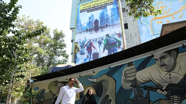 epa11662134 Iranians walk past an anti-Israeli billboard with a sentence reading in Persian and Hebrew, 'Israel is no longer a safe place for living' at the Palestine Square in Tehran, Iran, 16 October 2024. Iran fired more than 180 ballistic missiles directed at Israel late on 01 October 2024, in a 'retaliation for different assassinations' carried out by Israel and 'the crimes in Palestine and Lebanon', the Islamic Revolutionary Guard Corps (IRGC) said. Israel's prime minister Benjamin Netanyahu said that Iran will pay for the 'big mistake'. EPA/ABEDIN TAHERKENAREH