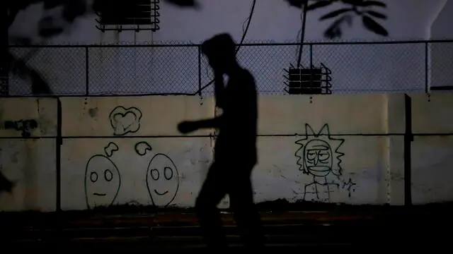 epa11350936 A person walks down a street without electricity in Havana, Cuba, 17 May 2024 (issued 18 May 2024). Recent blackouts in Cuba have prompted concerns about the government's plan to enhance the electrical system in July and August, the months with the highest demand and temperatures. The objective is to eliminate the link between power outages and protests. EPA/ERNESTO MASTRASCUSA