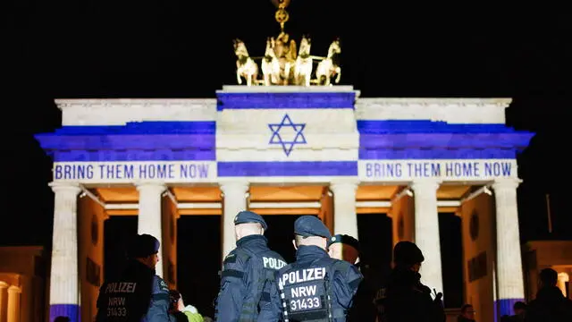 epaselect epa11648111 Police officers stand in a group in front of the Brandenburg Gate that is illuminated in the colors of the Israeli national flag in commemoration of the attack on Israel on 07 October and reads, in reference to the hostages, abducted by Hamas terror organization on 07 October 2023, 'Bring them home now' in Berlin, Germany, 07 October 2024. 07 October 2024 marks one year since the Palestinian militant group Hamas launched a surprise attack on Israel, killing 1,200, and one year since Israel began its war on Gaza, killing more than 41,000 and destroying the Palestinian enclave. EPA/CLEMENS BILAN