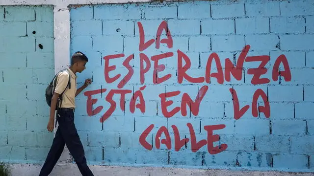 epa11667179 A student walks past graffiti reading 'Hope is in the street' in Caracas, Venezuela, 10 October 2024 (issued 18 October 2024). Public education in Venezuela is currently in a state of 'emergency' primarily due to a shortage of teachers, according to union representatives. The Venezuelan government is attempting to address this situation through various programs, including reaching out to retired educators to encourage them to return to teaching and offering incentives to entice former teachers back into the classroom, many of whom left due to low salaries. EPA/MIGUEL GUTIERREZ