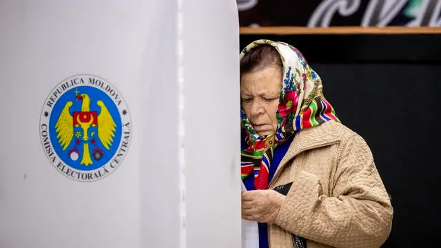 epa11671930 A woman examines her ballot paper in a polling station in Hrusevo village, Moldova, 20 October 2024. Moldova holds presidential election and a referendum on whether to enshrine in the Constitution the country's path to EU membership on 20 October. EPA/DUMITRU DORU