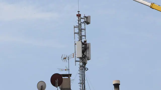 Un operaio monta un antenna di telefonia mobile su di un palazzo, Milano, 06 luglio 2022. ANSA / PAOLO SALMOIRAGO