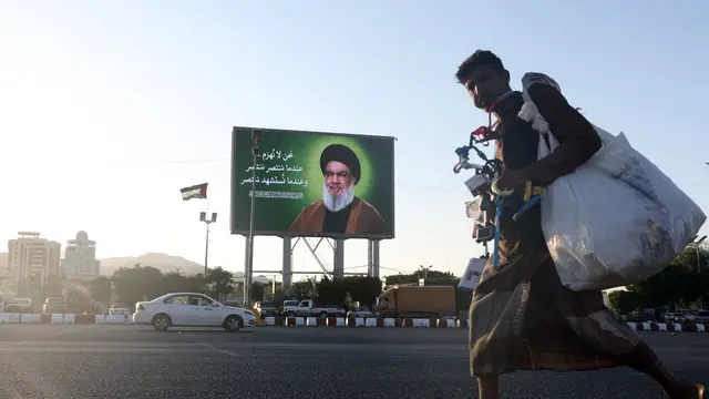 epa11662913 A hawker walks past a digital billboard showing Lebanon's Hezbollah late leader Hassan Nasrallah in Sana'a, Yemen, 16 October 2024. Nasrallah was killed in an Israeli strike on Beirut on 27 September. EPA/YAHYA ARHAB