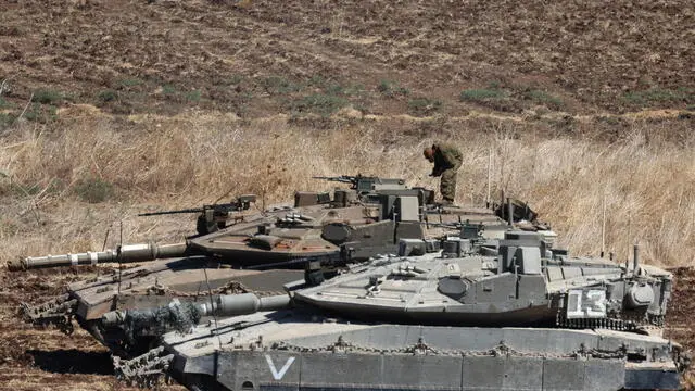 epa11627948 An Israeli soldier stands on a tank as they gather at an undisclosed location in northern Israel, 27 September 2024. Israel's military stated on 27 September, that the Israel Air Force (IAF) launched dozens of strikes targeting Hezbollah cells and infrastructure in several areas in southern Lebanon. EPA/ATEF SAFADI