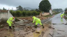 epa11690258 Several workers cleans the approach road to the village of Manuel after torrential rainfalls, in Valencia, eastern Spain, 29 October 2024. Heavy rains are hitting the region during the day. EPA/NATXO FRANCES