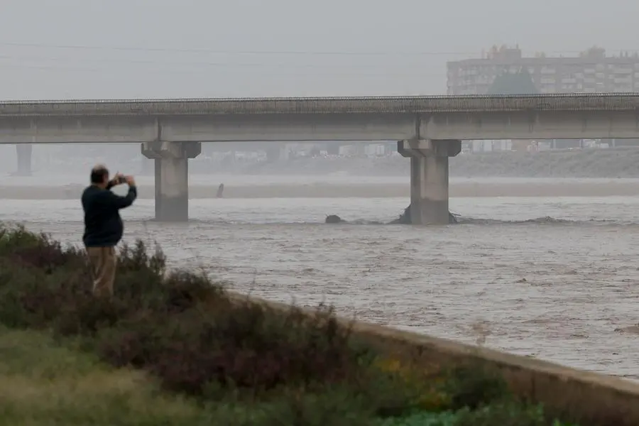 epa11691867 A man takes photos of the Turia River after heavy rainfalls hit the city of Valencia, eastern Spain, 30 October 2024. The State Meteorological Agency (AEMET) has issued red alerts for rainfall in multiple regions of the province of Valencia, caused by the severe storm DANA.The storm has impacted multiple areas of the city, resulting in the loss of at least 13 lives due to the flooding. EPA/Biel Alino