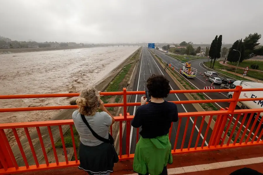 epa11691923 Two people stand on a bridge overlooking the Turia River, which is experiencing increased water levels after heavy rainfalls hit the city of Valencia, eastern Spain, 30 October 2024. The State Meteorological Agency (AEMET) has issued red alerts for rainfall in multiple regions of the province of Valencia, caused by the severe storm DANA. The storm has impacted multiple areas of the city, resulting in the loss of at least 13 lives due to flooding. EPA/BIEL ALINO