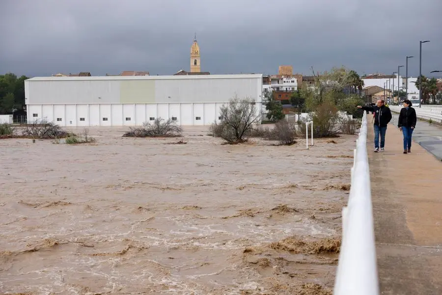 epa11690550 People look the flow of the Magre river, in Alfarp, Valencia, Spain, 29 October 2024. The State Meteorological Agency (AEMET) has activated red alerts for rain in various areas of the province of Valencia due to heavy rainfall caused by the storm DANA that is hitting several areas of Spain. EPA/ANA ESCOBAR