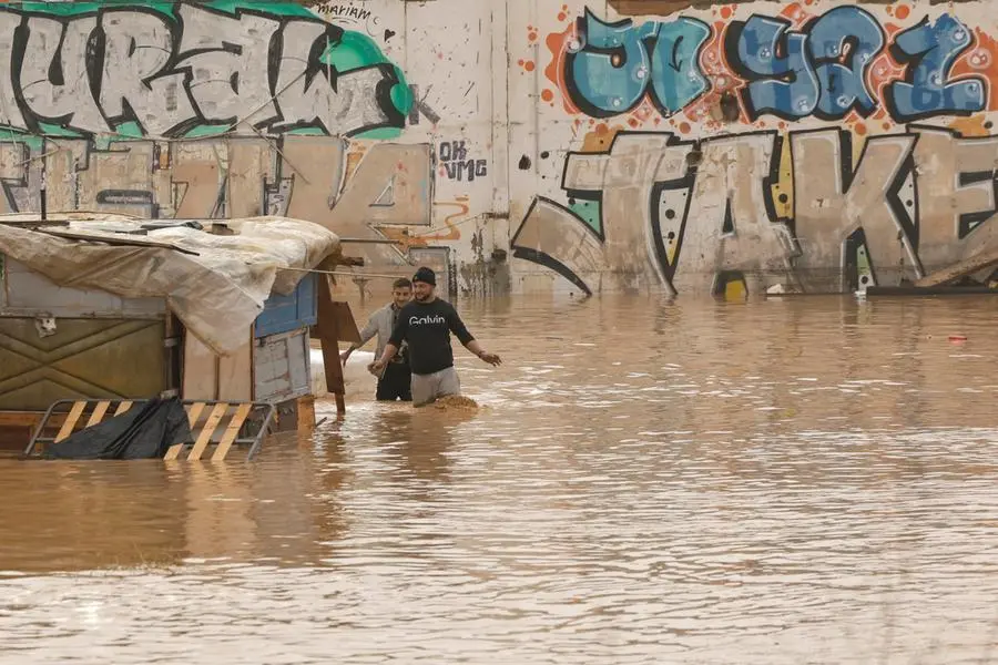 epa11691924 People walk through a flooded area next to the V-30 highway, which was submerged by significant rainfall in the city of Valencia, eastern Spain, on 30 October 2024. The State Meteorological Agency (AEMET) has issued red alerts for rainfall in multiple regions of the province of Valencia, caused by the severe storm DANA. The storm has impacted multiple areas of the city, resulting in the loss of at least 13 lives due to the flooding. EPA/BIEL ALINO