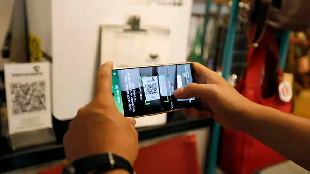 epa10791501 A customer scans a QR code for payments with their phone at a coffee shop in Hanoi, Vietnam 09 August 2023. Cashless payments, including mobile phone and QR code payments, have soared in popularity in Vietnam. QR code transactions rose by 151.14 percent in volume in the first five months of 2023, according to media reports. EPA/LUONG THAI LINH