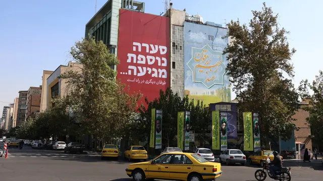 epa11688826 Iranians drive past a huge anti-Israeli billboard reading 'another storm on the way' at the Palestine Square in Tehran, Iran, 28 October 2024. Iranian supreme leader Ayatollah Ali Khamenei said on 27 October that Israel's strike on Iran should neither be exaggerated nor underestimated. Israel Defense Forces (IDF) spokesman Daniel Hagari confirmed on 26 October that the Israeli Army, Tsahal, conducted precise strikes on military targets in Iran. According to the Iran Air Defense Force, the Israeli attack was successfully countered by the country's integrated air defense system. EPA/ABEDIN TAHERKENAREH