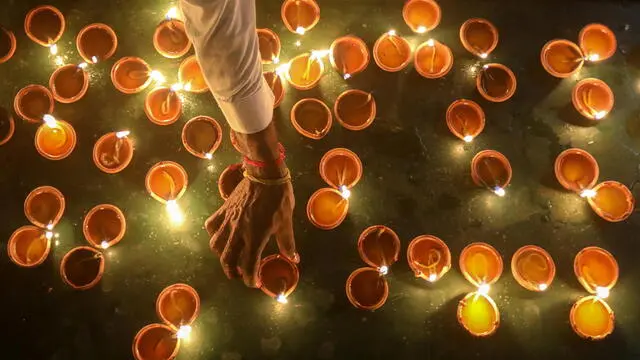 epa11693636 A Sri Lankan Hindu devotee lights oil lamps during the Diwali festival at a Hindu temple in Colombo, Sri Lanka, 31 October 2024. Diwali is one of the most popular festivals in Hinduism and is celebrated by Hindus worldwide. Also known as the festival of lights, it symbolizes the victory of good over evil and commemorates Lord Ram's return to his kingdom, Ayodhya, after completing a 14-year exile. EPA/CHAMILA KARUNARATHNE