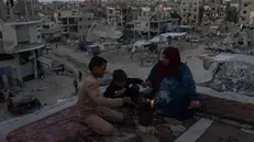 epa11634230 Members of a Palestinian family gather around a fire on the roof of their destroyed house in Khan Yunis, southern Gaza Strip, 30 September 2024. The ongoing conflict has left the population with widespread destruction, including the disruption of basic services such as water, electricity and sanitation. More than 41,300 Palestinians and over 1,400 Israelis have been killed, according to the Palestinian Health Ministry and the Israel Defense Forces (IDF), since Hamas militants launched an attack against Israel from the Gaza Strip on 07 October 2023, and the Israeli operations in Gaza and the West Bank which followed it. EPA/HAITHAM IMAD