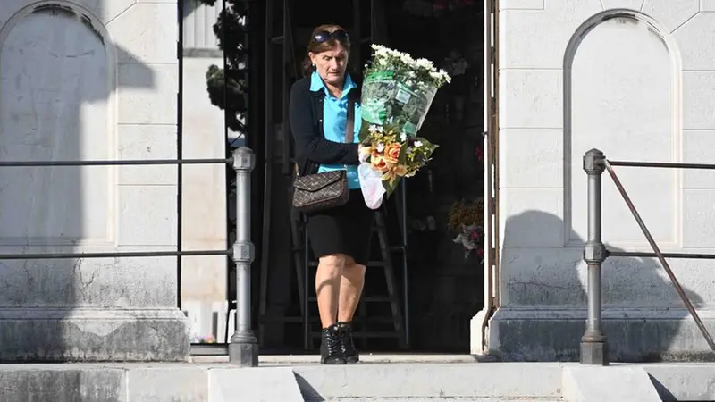 Una signora con i fiori al cimitero - Foto Marco Ortogni/Neg © www.giornaledibrescia.it