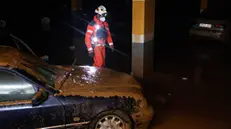 epa11700585 A firefighter stands next to a mud-covered car while searching for victims at an underground parking lot, in the municipality of Sedavi, province of Valencia, Spain, 04 November 2024. The devastating floods in Valencia and neighboring provinces have caused at least 213 fatalities as efforts to search for missing people, provide supplies and care for the victims continue almost one week since the DANA (high-altitude isolated depression) weather phenomenon hit the east of the country. EPA/ANA ESCOBAR