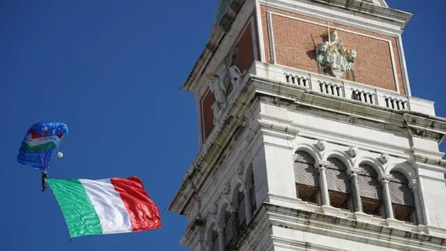 Paracadutisti dell'Esercito sorvolano piazza San Marco con la bandiera italianain occasione delle celebrazioni per la Giornata dell'Unità nazionale e delle Forze Armate cui ha preso parte anche il presidente della Repubblica Sergio Mattarella. Venezia, 4 novembre 2024 ANSA/Andrea Merola