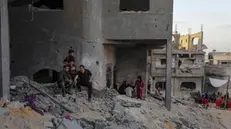 epa10628549 Palestinian sit amidst the rubble of their destroyed family houses, following Israeli strikes in Beit Lahiya town, northern Gaza Strip, 14 May 2023. Israel and Islamic Jihad movement agreed to an Egyptian-brokered truce late 14 May. Israel has carried out several attacks against the military leadership of the Palestinian Islamic Jihad movement, in retaliation to rockets being fired towards Israel from in the Gaza Strip. EPA/MOHAMMED SABER