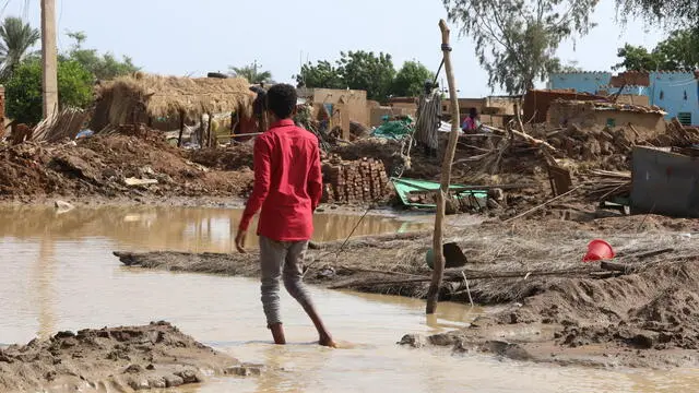 epa10135163 Sudanese people stand amid a flooded area of Al Jazirah state, Sudan, 23 August 2022. According to the Sudanese Council for Civil Defense, at least 79 people died in incidents related to the recent floods in the country. Thousands of homes were damaged due to the floods that affected South Darfur, North Kordofan, and Al Jazirah state. EPA/MOHND AWAD